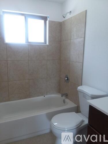 A bathroom with a toilet, tub, and window.