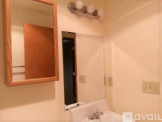 A bathroom with a mirror, sink, and a door.