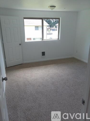 A room with a carpeted floor, a window, and a door.