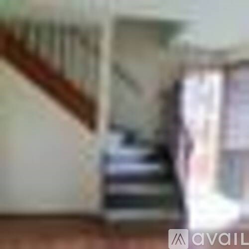 A staircase with a wooden handrail and a white wall.