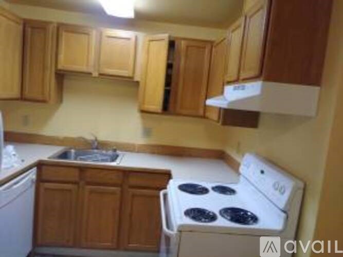 A kitchen with wooden cabinets and a white stove top oven.