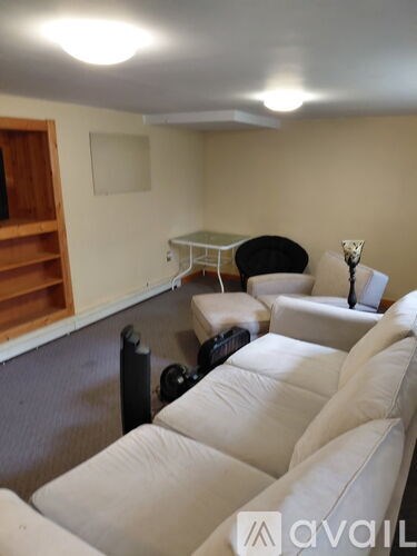 A living room with white couches and a wooden shelf.