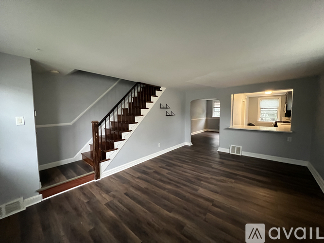 A spacious room with wooden floors and a staircase leading to another level.
