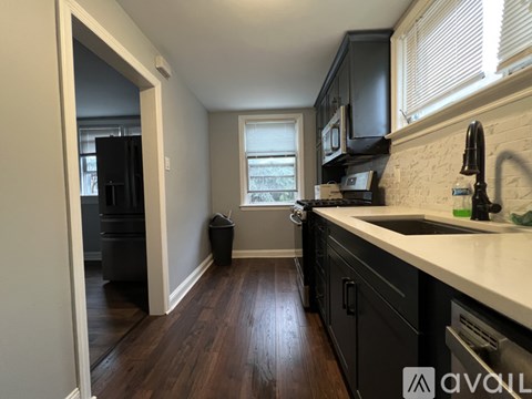 A kitchen with black cabinets and a wooden floor.