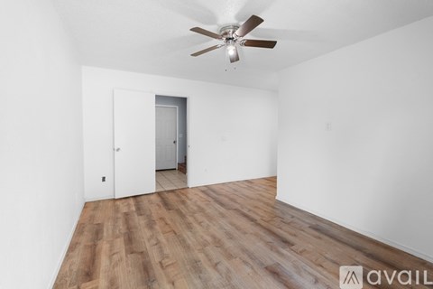 A room with a ceiling fan and wooden flooring.