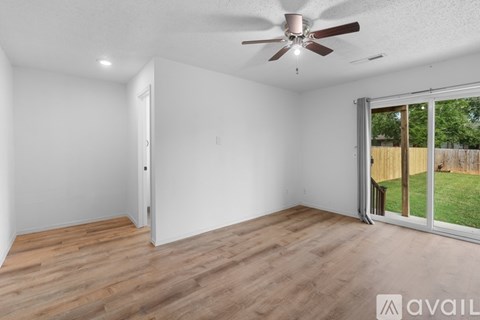 A room with a ceiling fan and sliding glass doors.