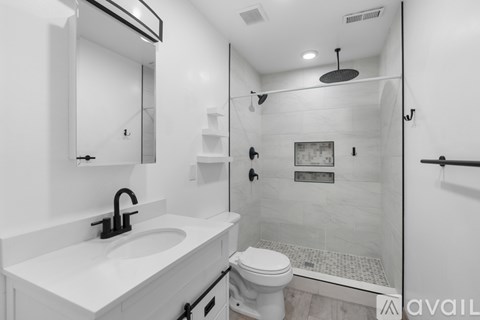 A white bathroom with a toilet, sink, and shower.