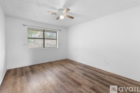 A room with a ceiling fan and a window with blinds.