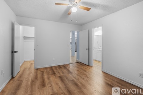 A spacious room with wooden flooring and a ceiling fan.