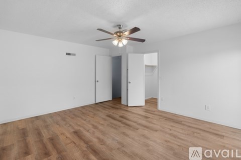 A room with a ceiling fan and wooden flooring.