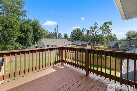 A wooden deck with a railing and a view of a residential area.