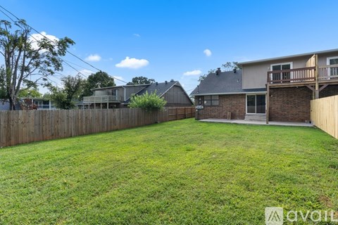 A backyard with a wooden fence and a house in the background.