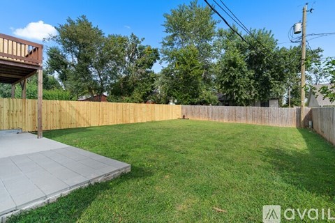 A backyard with a wooden fence and a concrete patio.