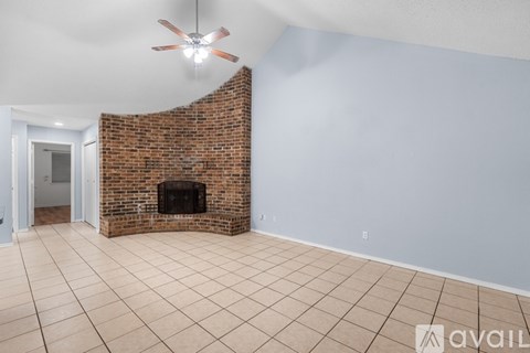 A room with a brick fireplace and a ceiling fan.