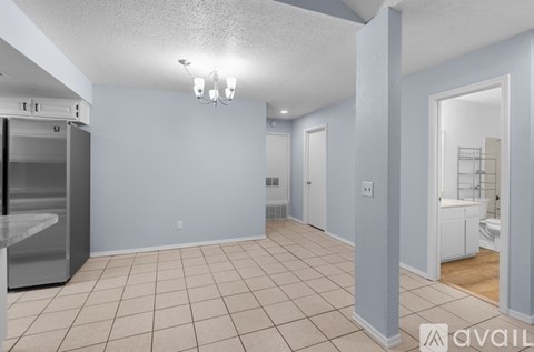 A spacious room with a kitchen appliance and a bathroom visible through the door.