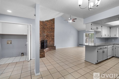 A living room with a fireplace and a kitchen area in the background.