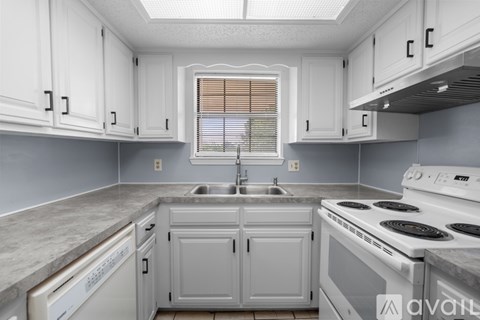 A kitchen with white cabinets and a white stove top oven.