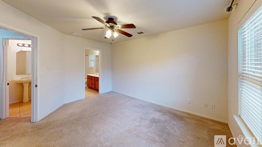 A spacious room with a ceiling fan and carpeted floor.