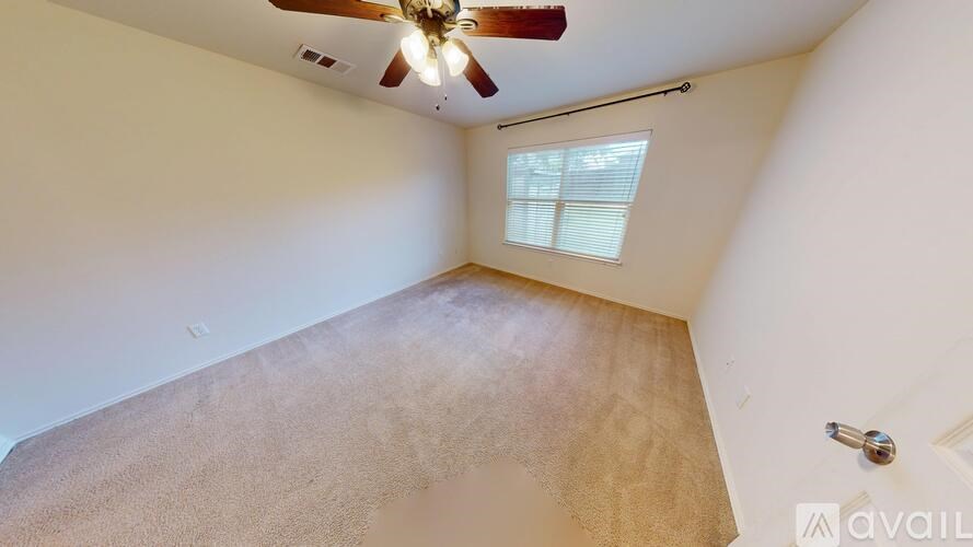 A room with a ceiling fan and a window with blinds.