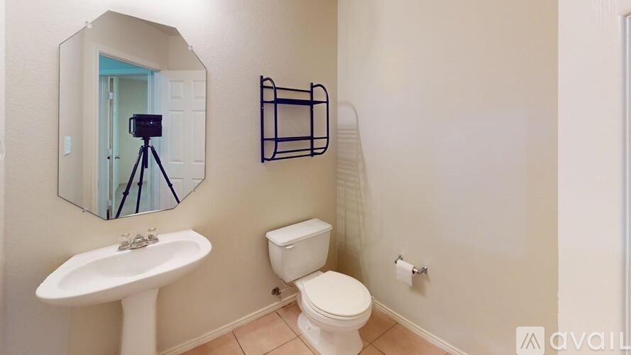 A bathroom with a toilet, sink, and mirror.