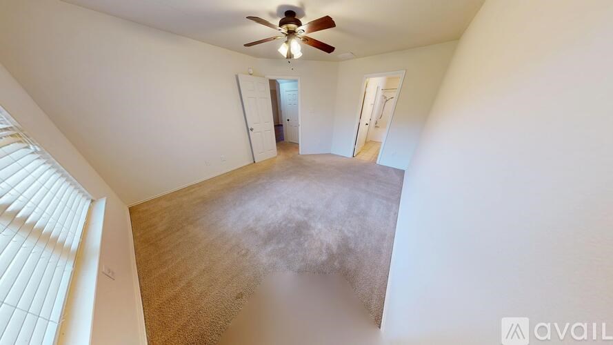 A room with a carpeted floor, a window, and a door.