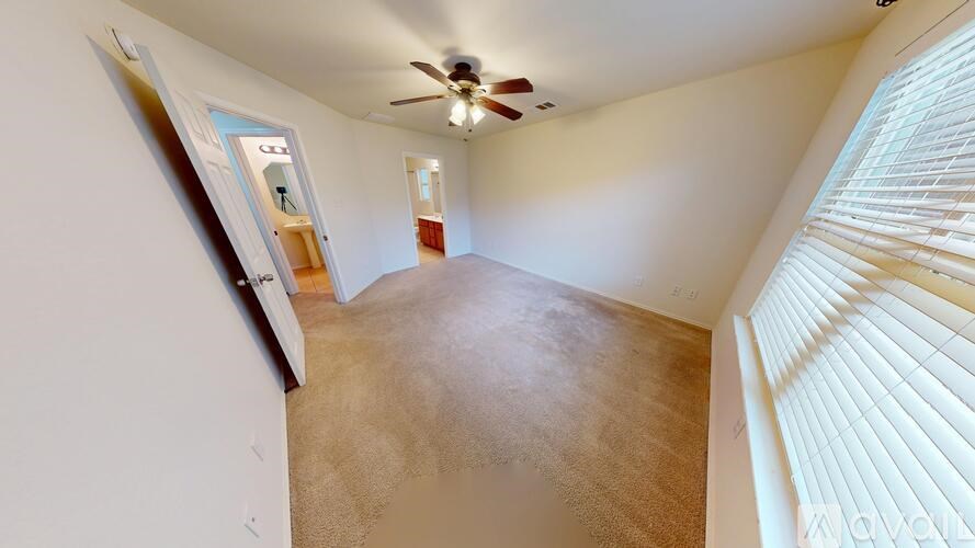A spacious room with a ceiling fan and carpeted floor.