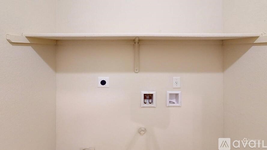 A white wall with a shelf and two small boxes on it.