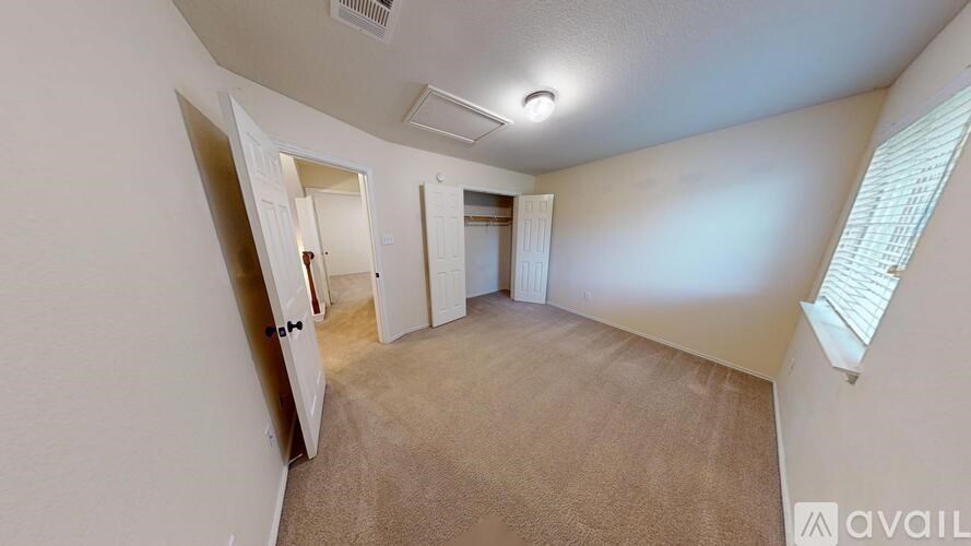 A room with beige carpet and white walls, with a door open to another room.