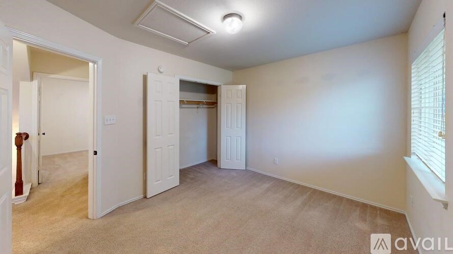 A room with a carpeted floor and two doors, one of which is open.