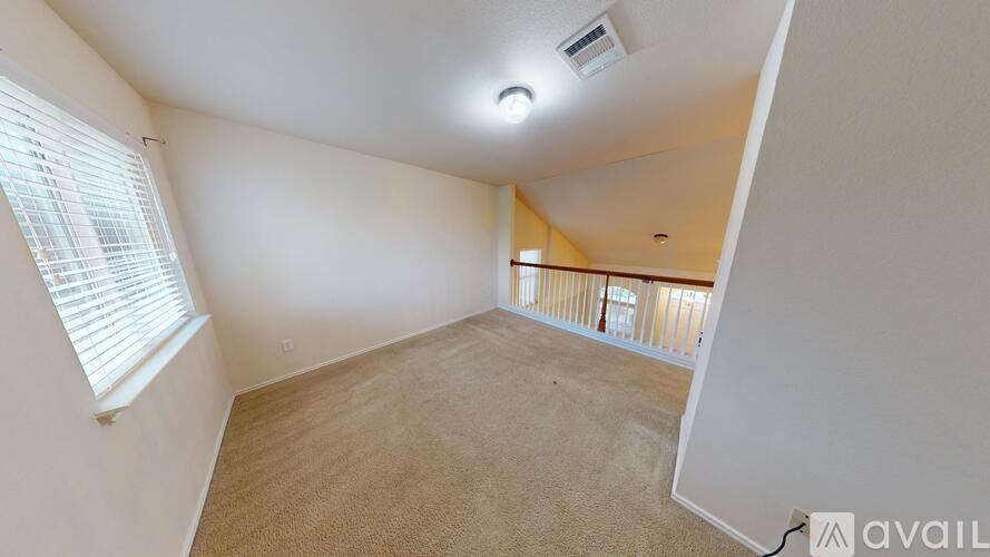 A room with a carpeted floor and a window with blinds.
