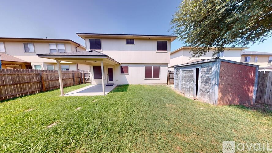 A house with a fence and a tree in front of it.