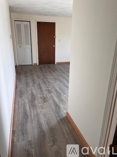 A hallway with a wooden door and a white door with blinds.