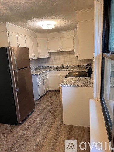 A kitchen with a black refrigerator and white cabinets.
