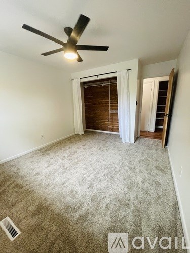 A room with a ceiling fan and carpeted floor.