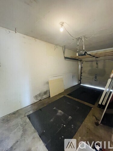 A room with a white wall and a black mat on the floor.