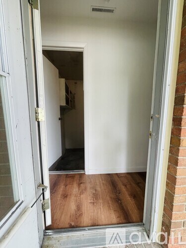 A white door is open to a room with a brick wall.