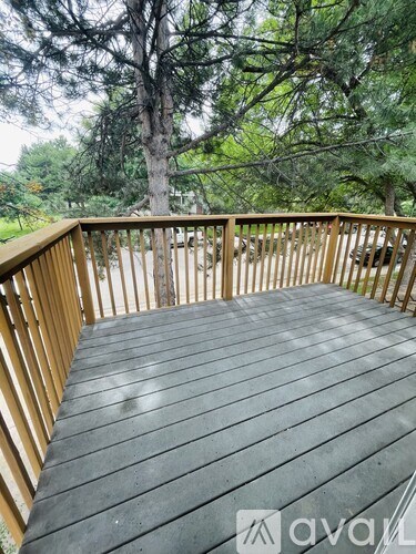 A wooden deck with a railing and trees in the background.