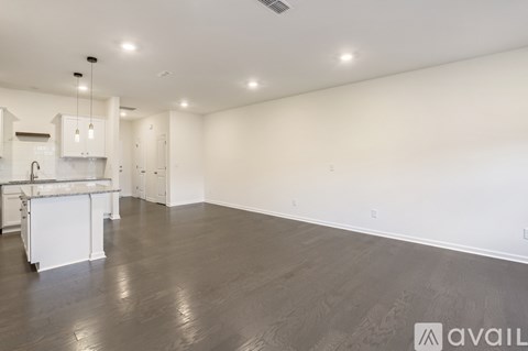 A spacious room with a kitchen area and a dining table.