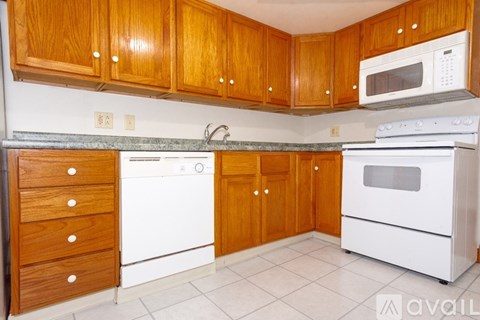 A kitchen with white appliances and wooden cabinets.