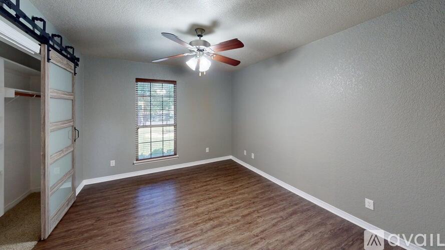A room with a ceiling fan and a window with blinds.