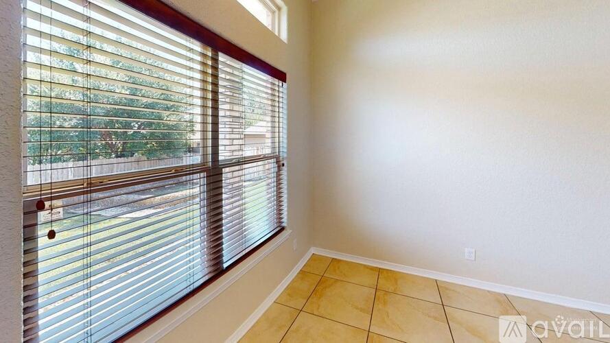 A room with tiled flooring and a window with blinds.