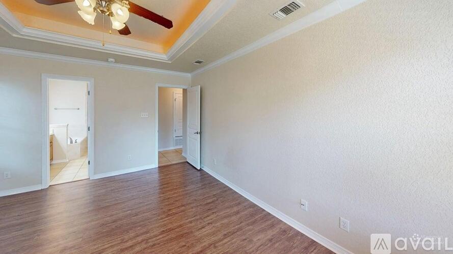 A spacious room with a ceiling fan and wooden flooring.