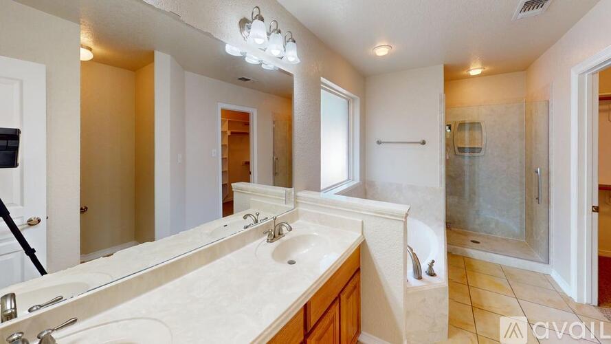 A bathroom with a large mirror, sink, and shower.