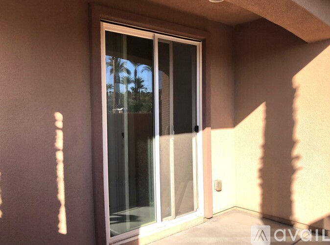 A sliding glass door with a view of palm trees outside.