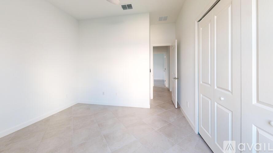 A spacious room with a white door and a tiled floor.