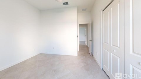 A spacious room with a white door and a tiled floor.