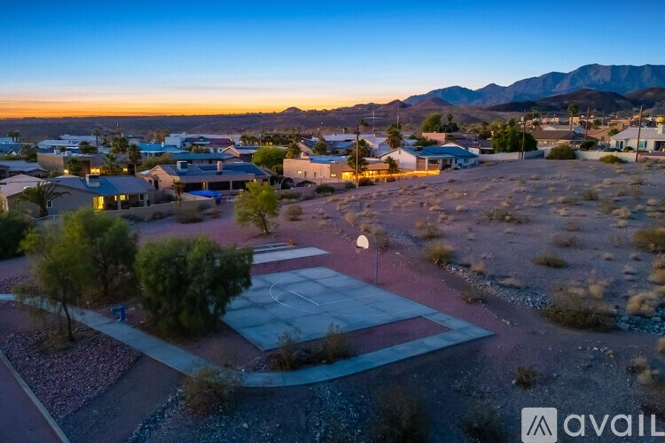 A sunset view of a neighborhood with houses and a basketball court.