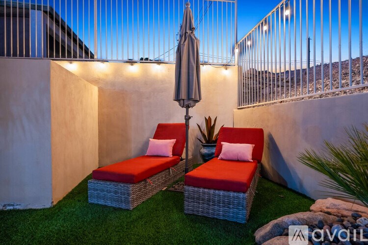 Two red cushioned chairs are placed on a lawn.