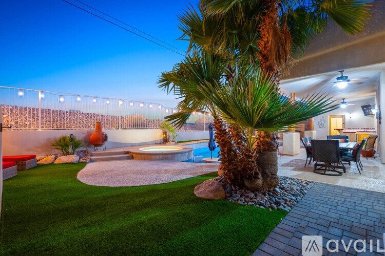 A backyard with a palm tree, a patio table, and a pool.