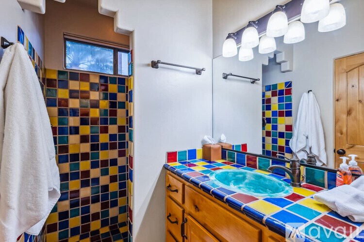 A bathroom with a multicolored tiled shower and sink.